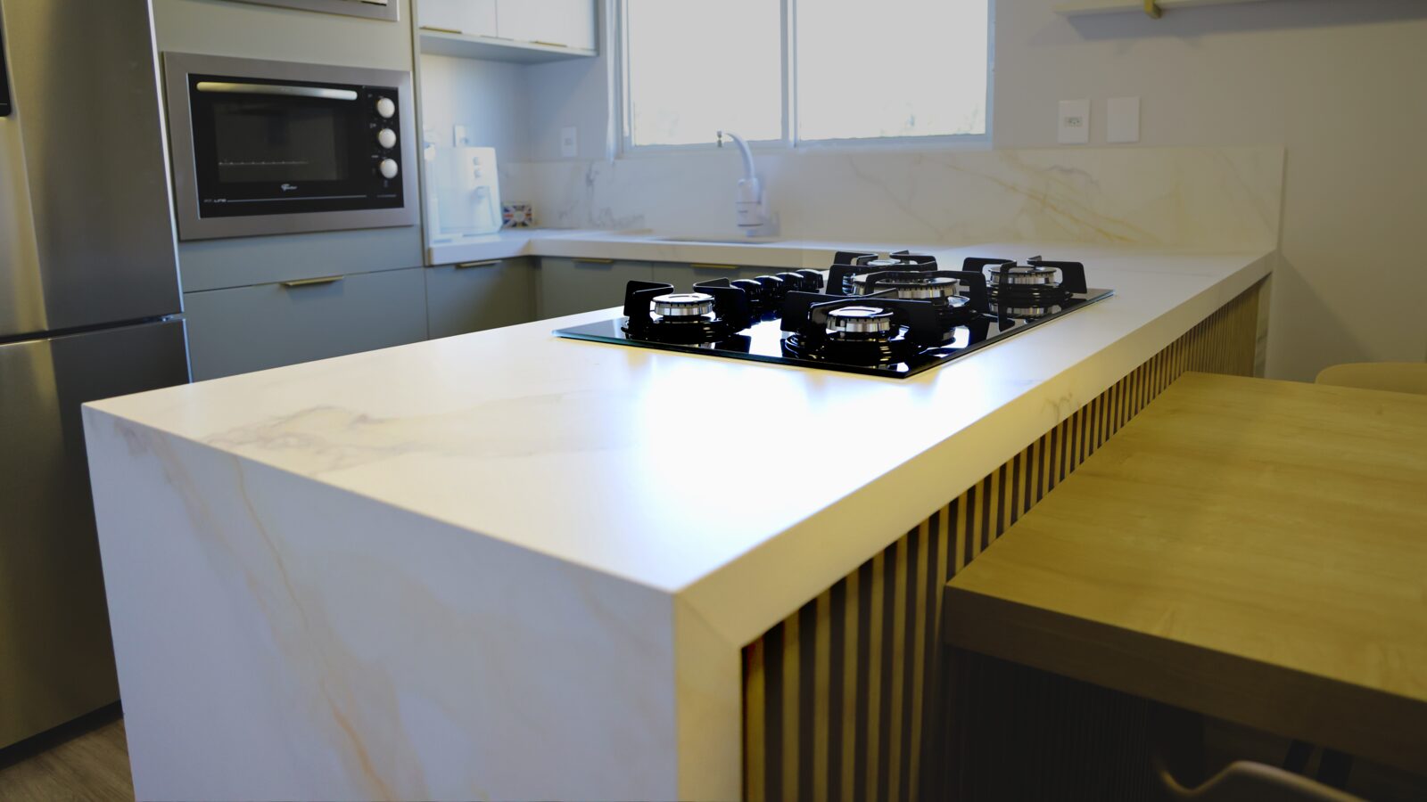 Cozinha linear com bancada e frontão na mesma pedra
